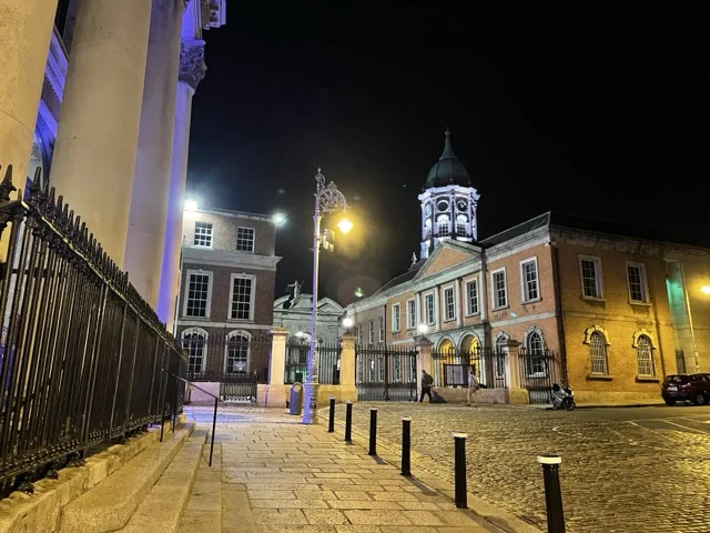 Illuminated Dublin Castle courtyard and cobbled street at night