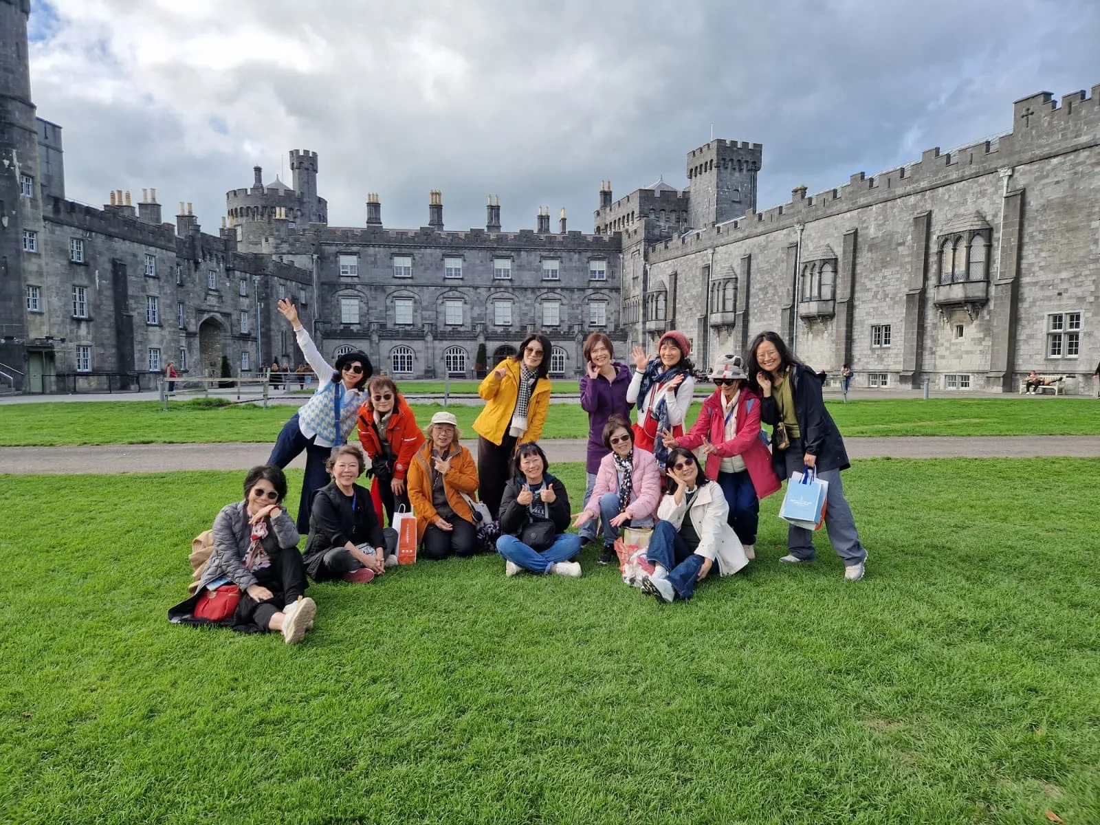 A group of adults together outdoors in front of a historic stone building